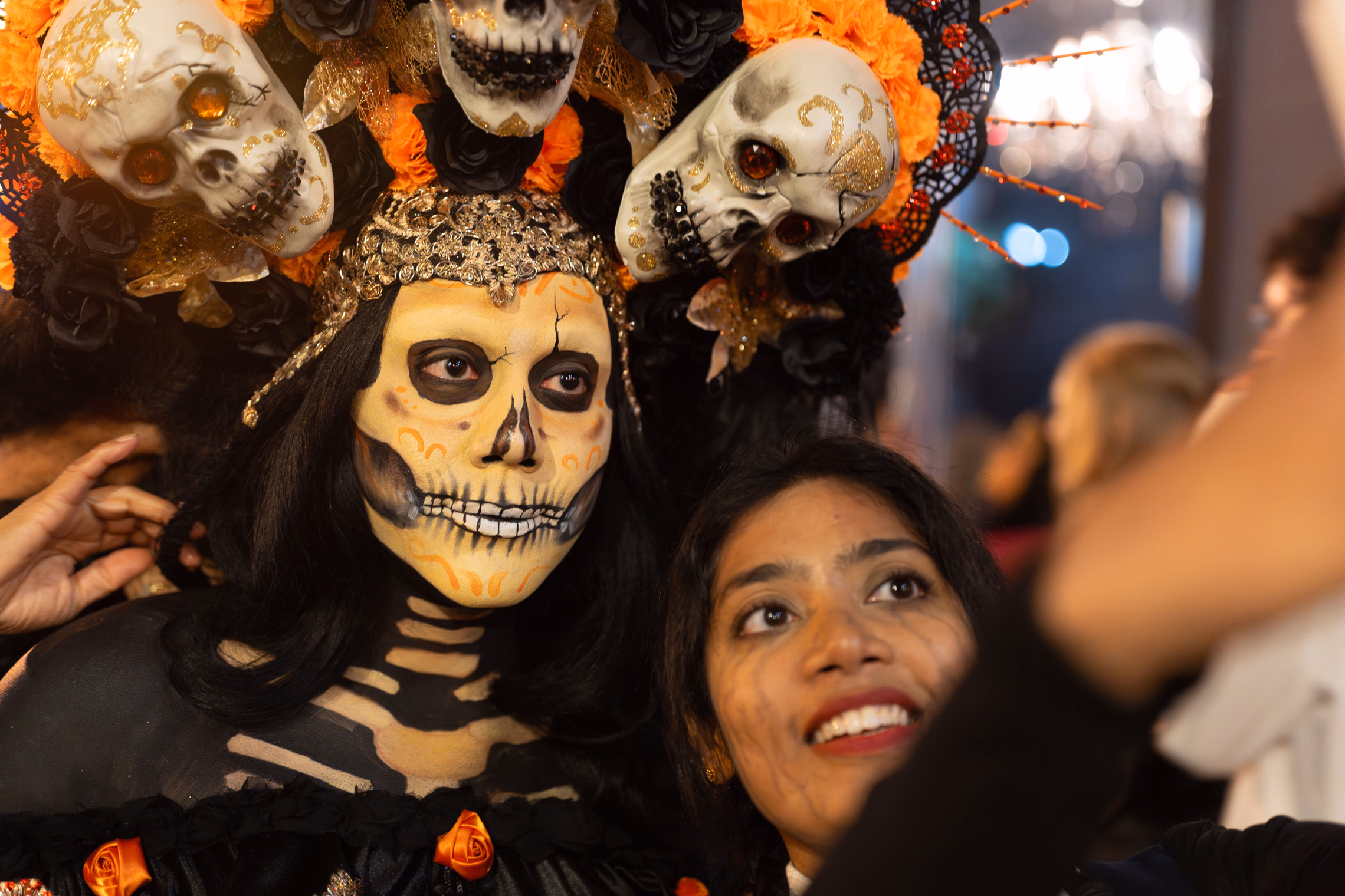 Adults in elaborate Halloween costumes and makeup gathered at a crowded nighttime party