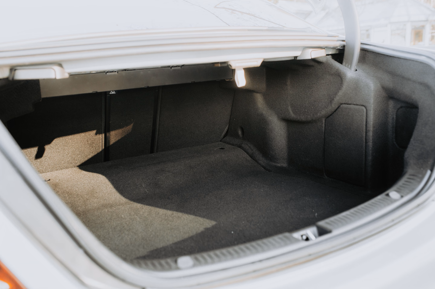 The open, empty carpeted trunk of a white sedan