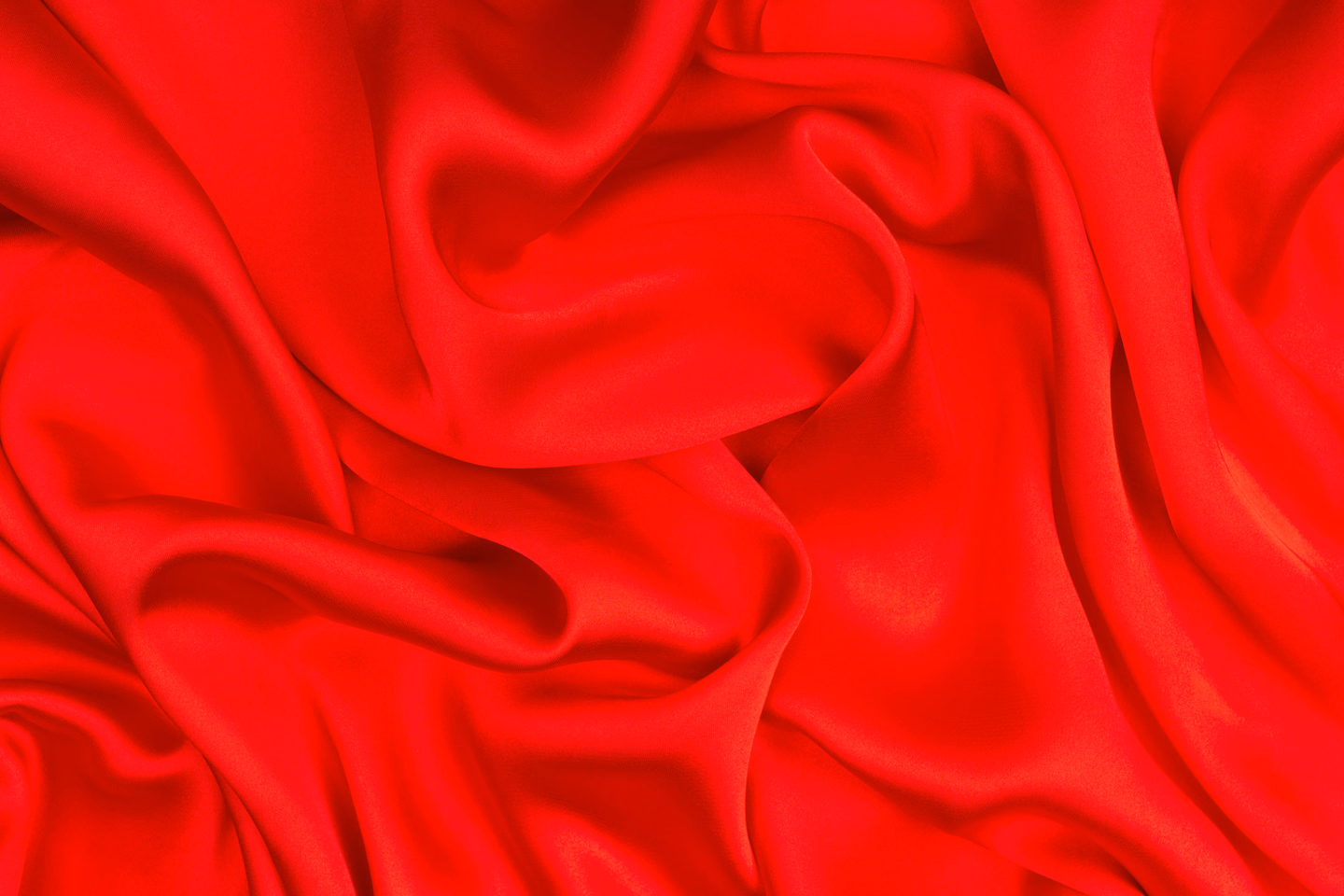 Close-up of bright red satin-finish fabric in deep, soft folds