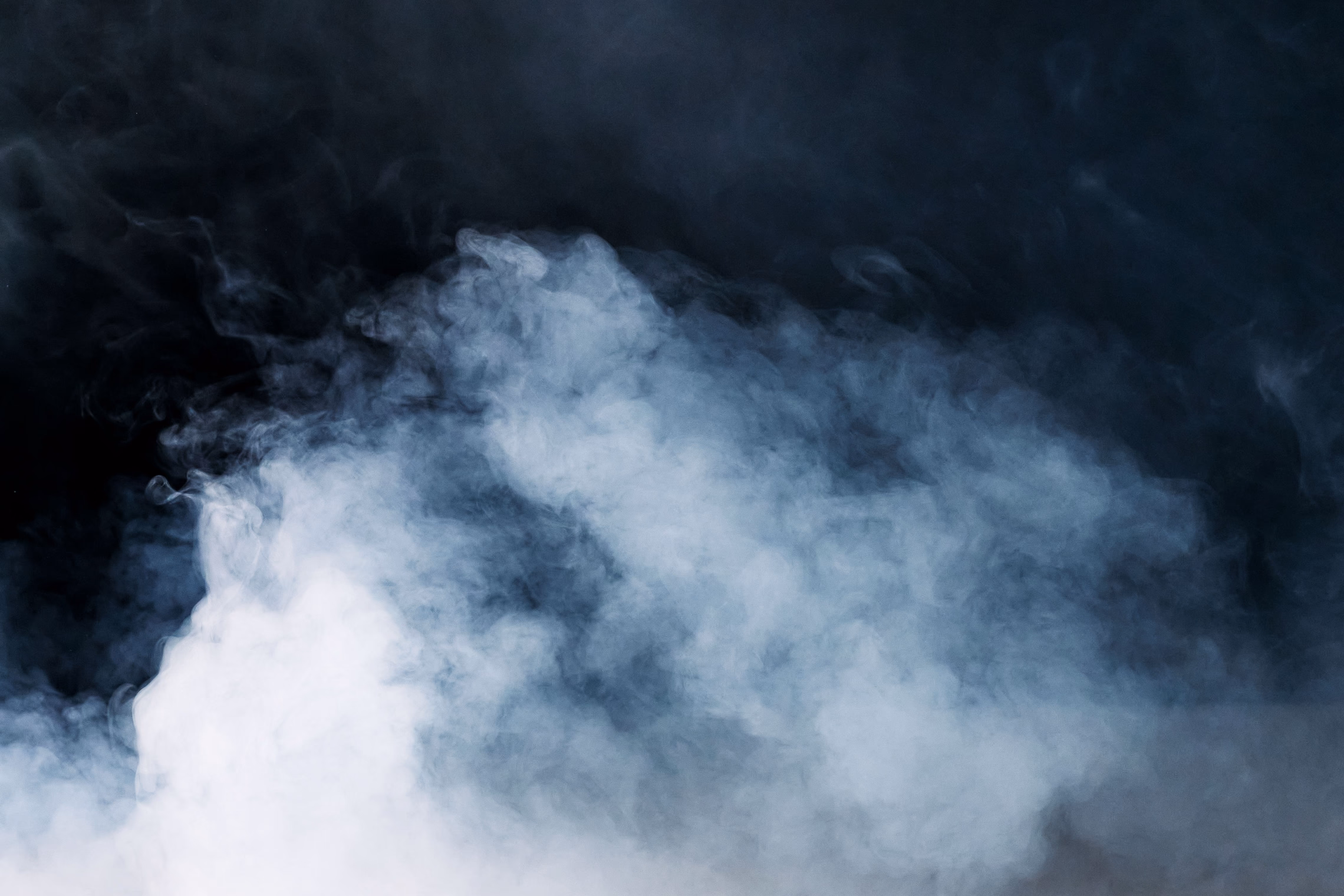Dense white fog drifting through a dark room, lit from behind