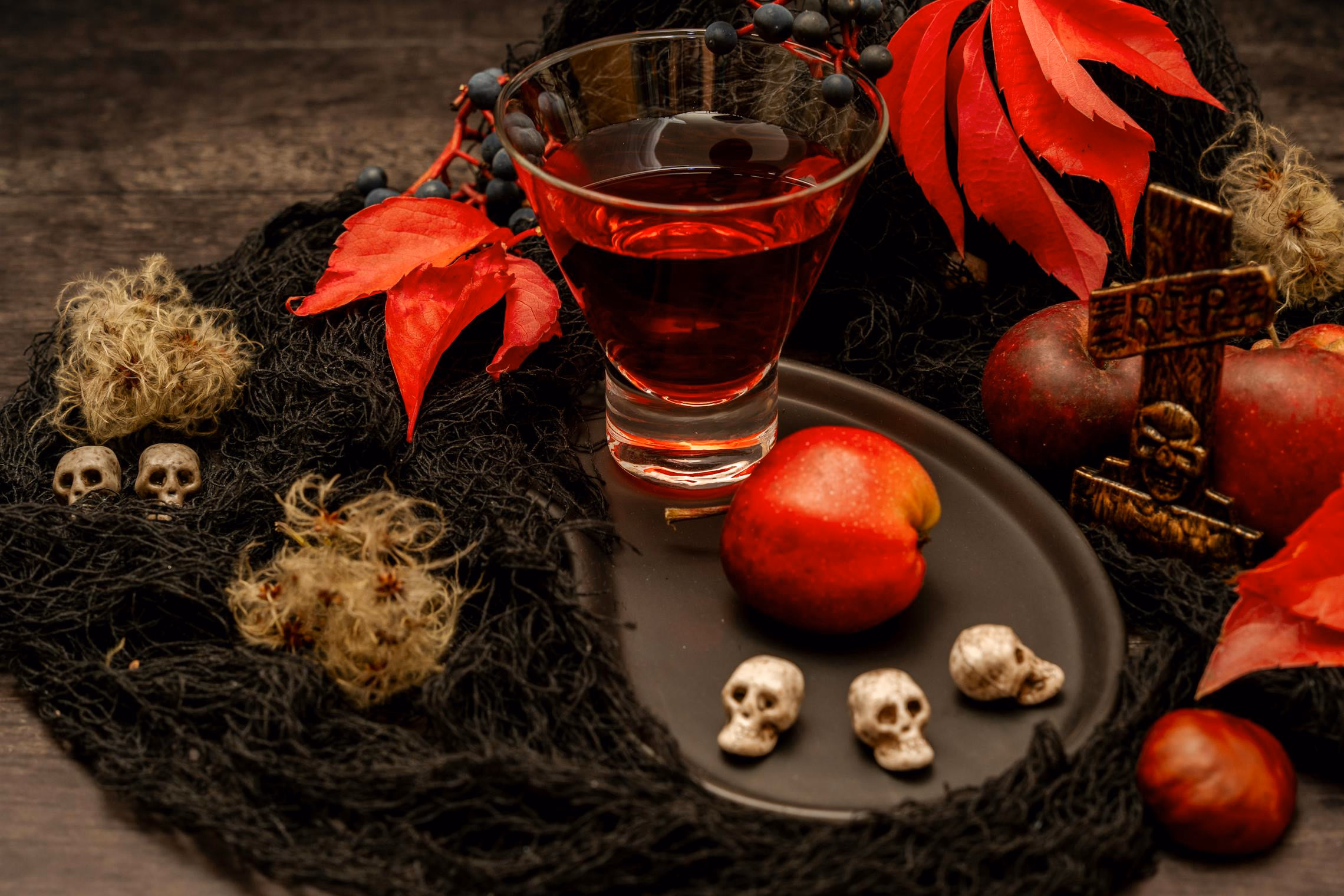 Dark-hued Halloween cocktails on a black marble bar with dry ice smoke curling around the glasses