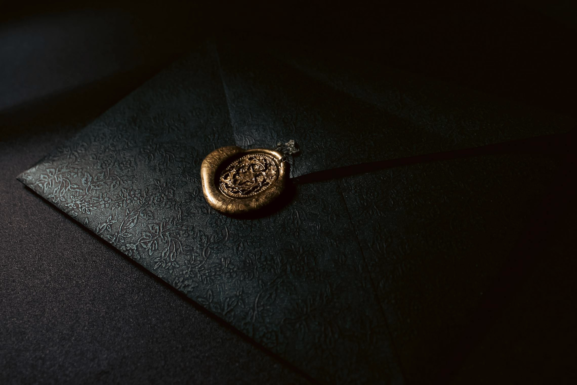 A black wax-sealed Halloween party invitation on dark parchment with gold calligraphy