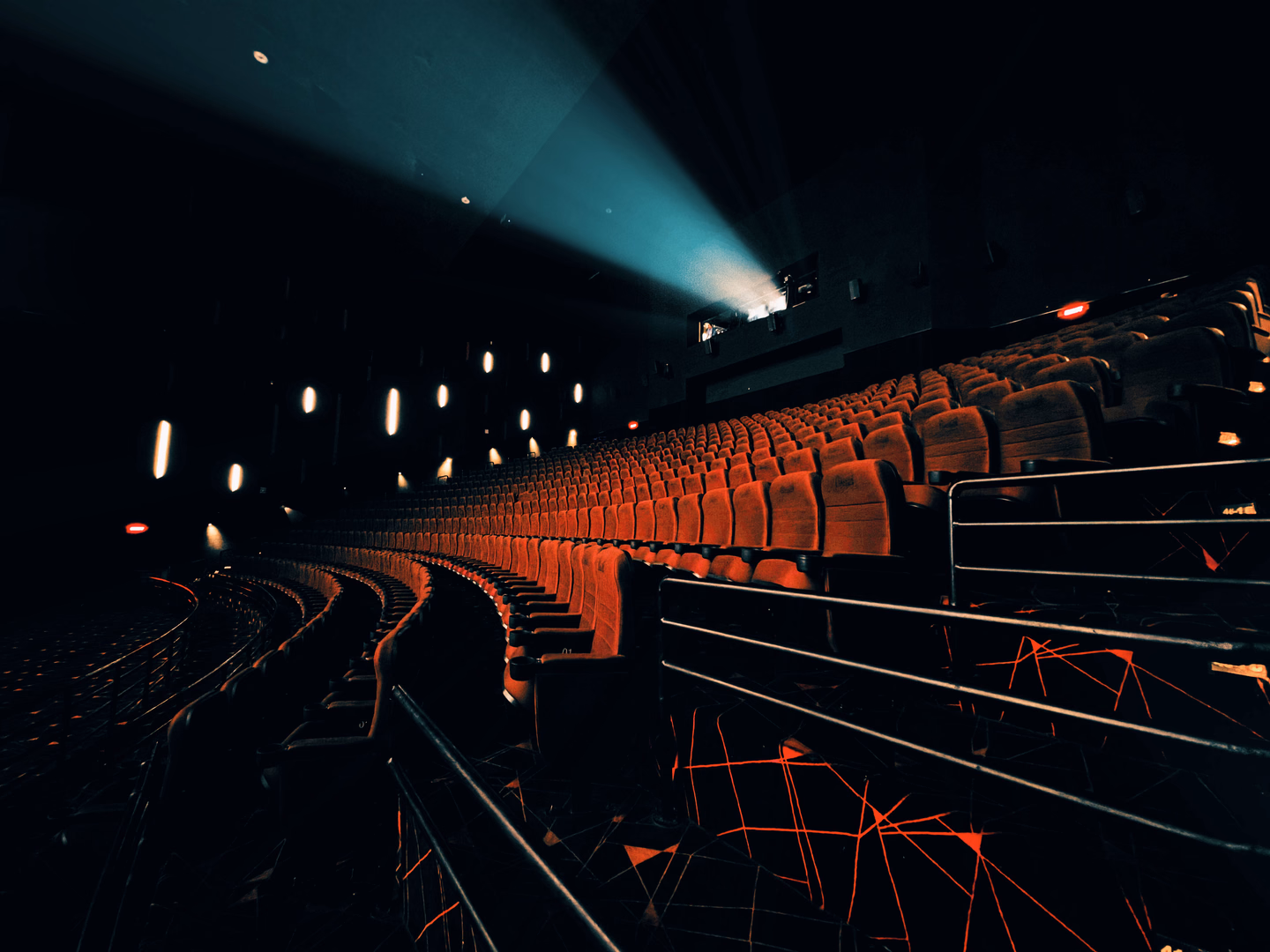 An empty theater in darkness, a projector beam cutting across the rows of seats