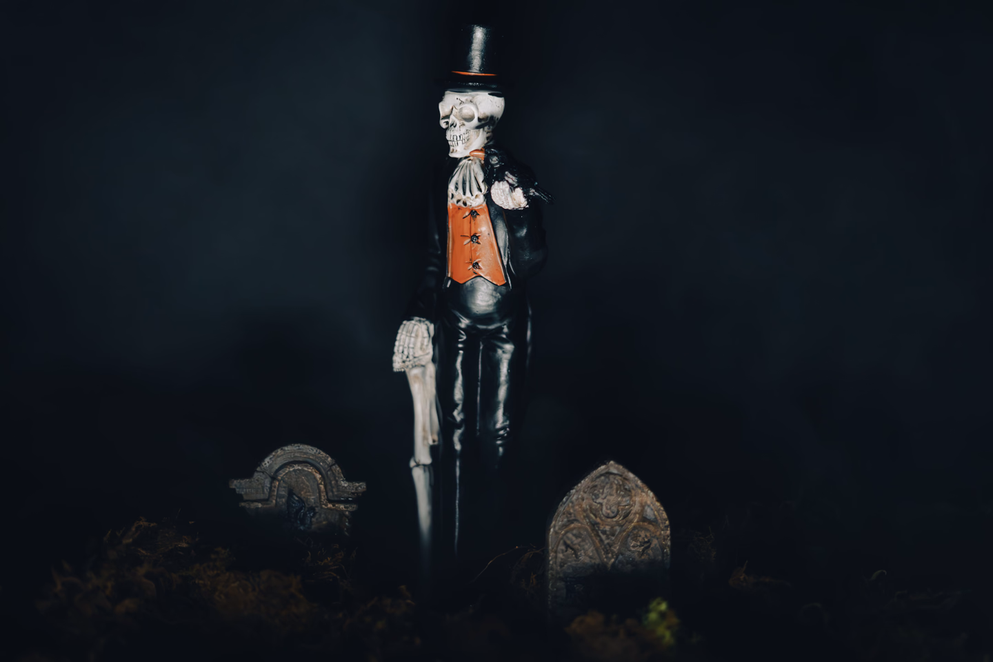 A skeleton figure in a tailcoat standing among dark graves at night