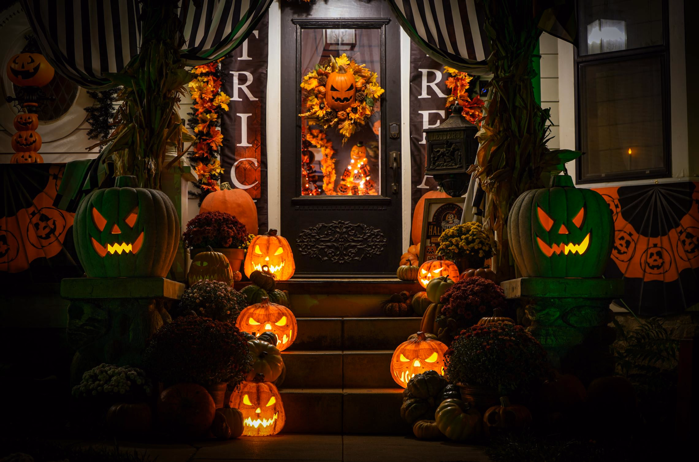 Gothic-decorated front porch with lanterns, carved pumpkins, and draped black fabric at dusk