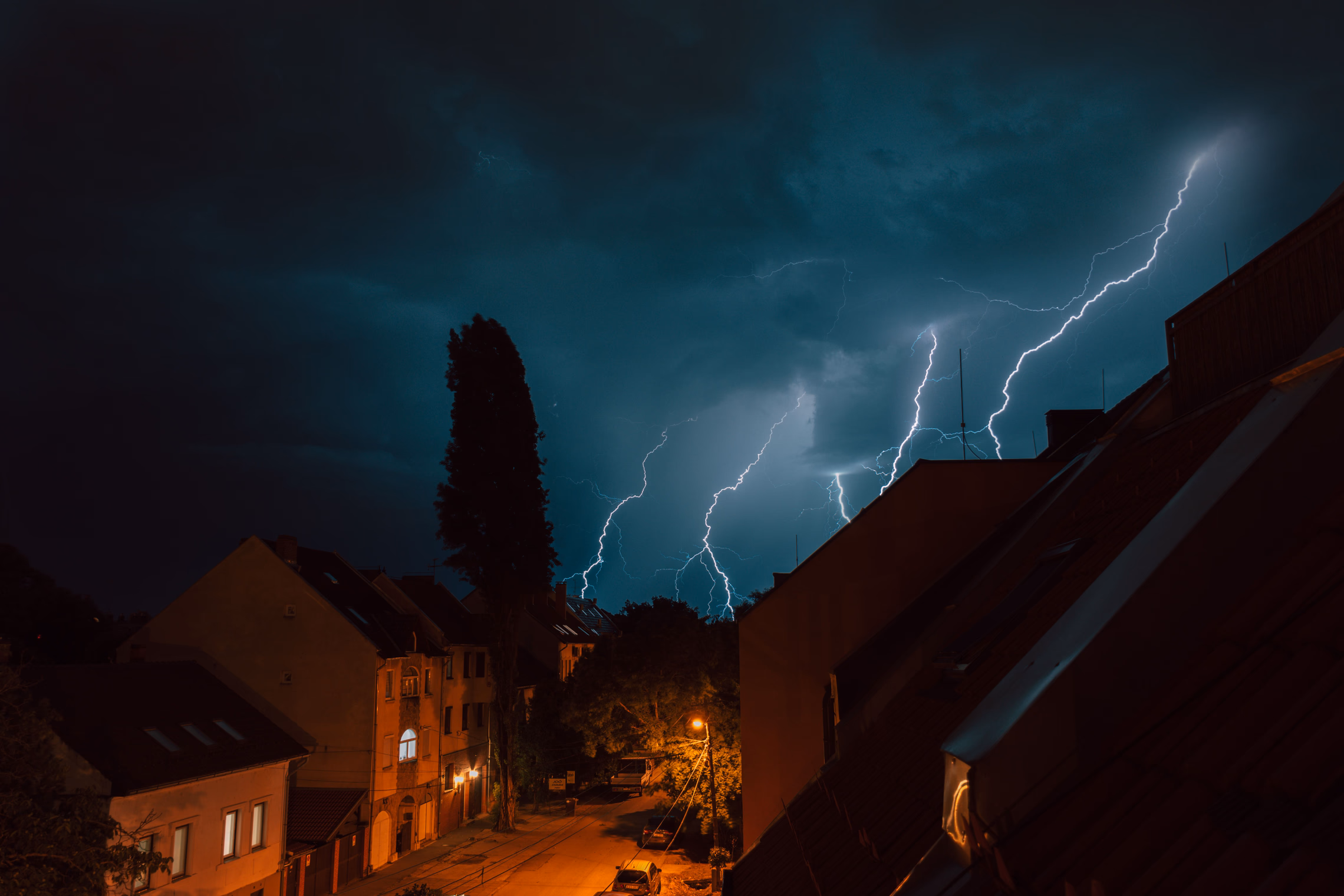 Lightning illuminating the night sky above a dark residential building