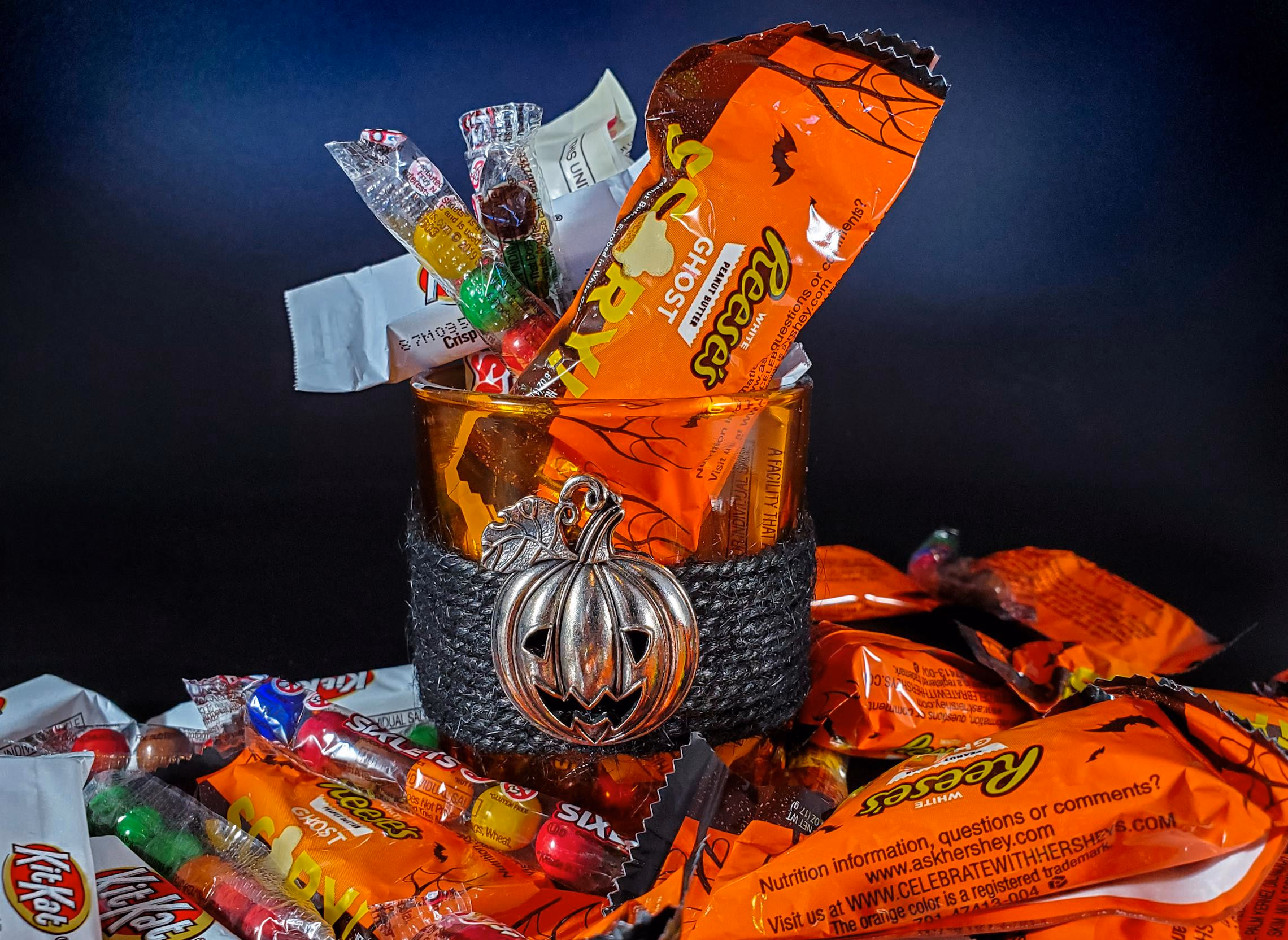 Overflowing bowl of assorted Halloween candy on a dark wooden table