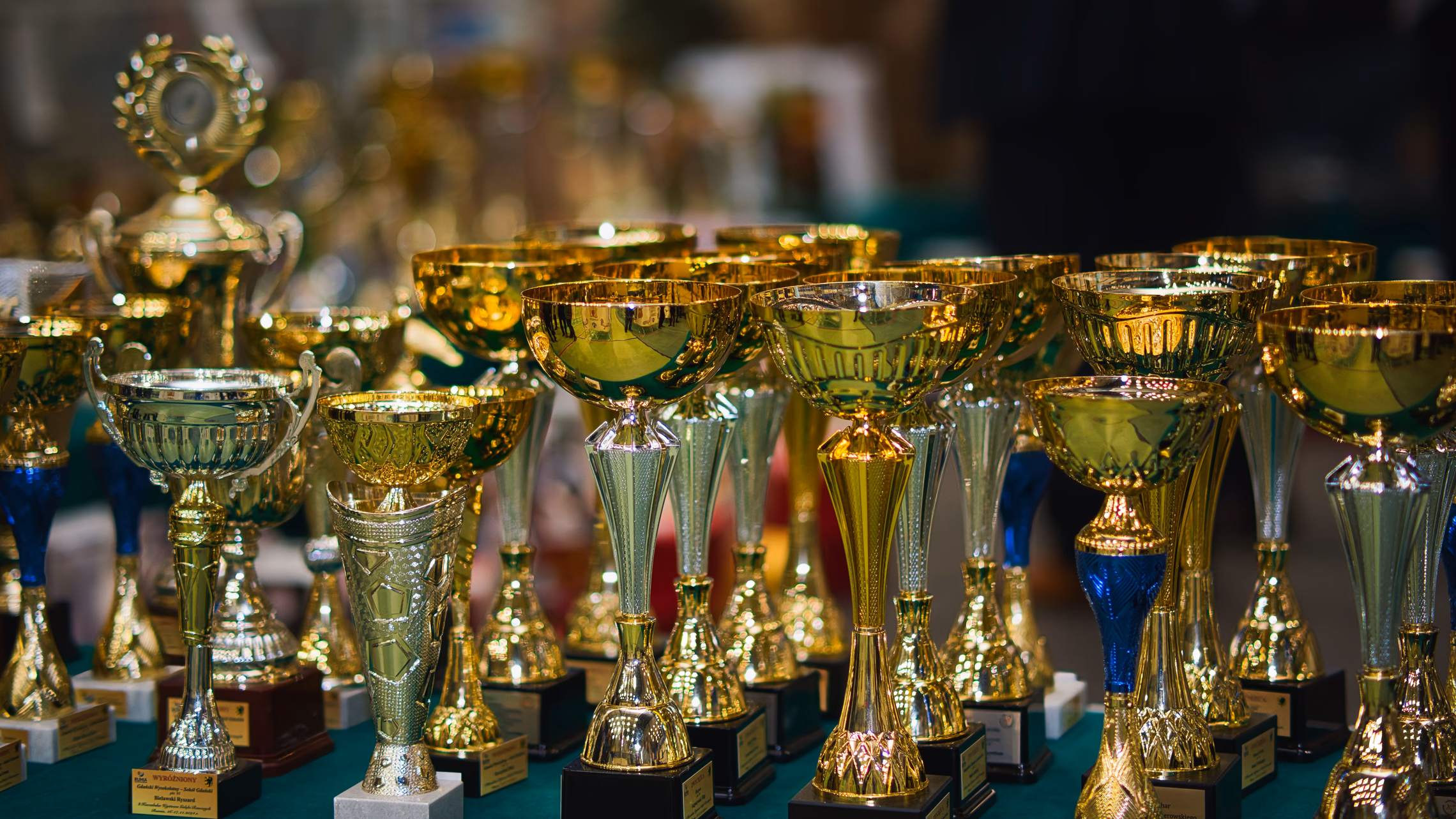 A row of gold trophies arranged on a table in warm low light