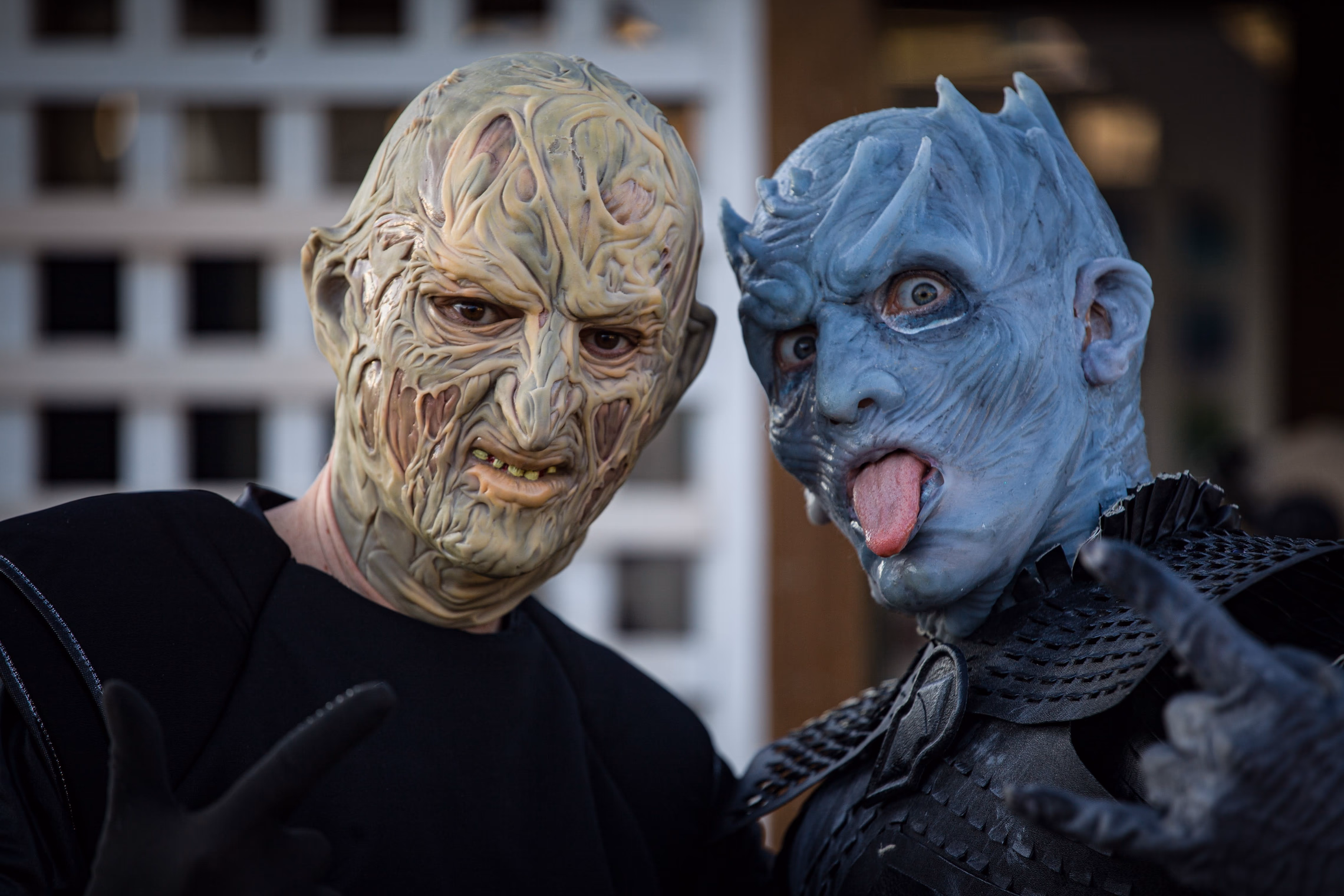 Two adults in detailed horror masks posing together for a Halloween photo shoot