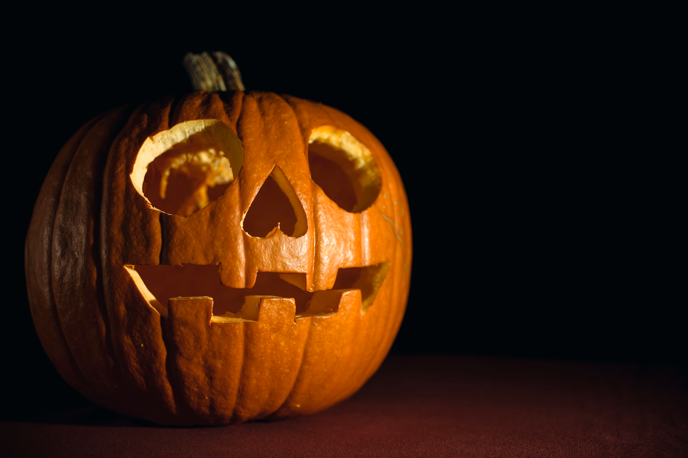 A carved jack-o'-lantern glowing against a dark background