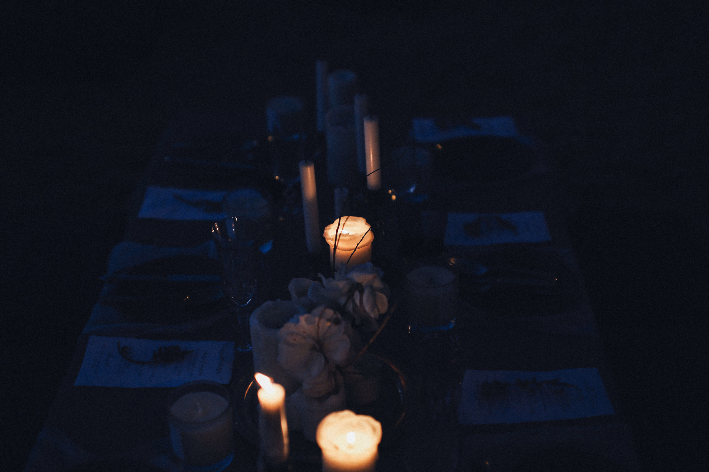 An elegant candlelit dinner table set in a dark room